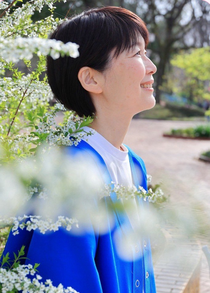 花のそばで穏やかにほほえむ、やよいさん